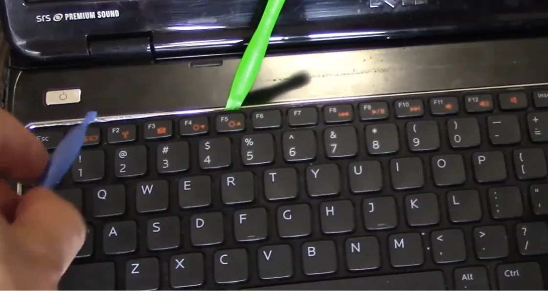 Spudger faisant levier le long du bord du clavier pour libérer les clips